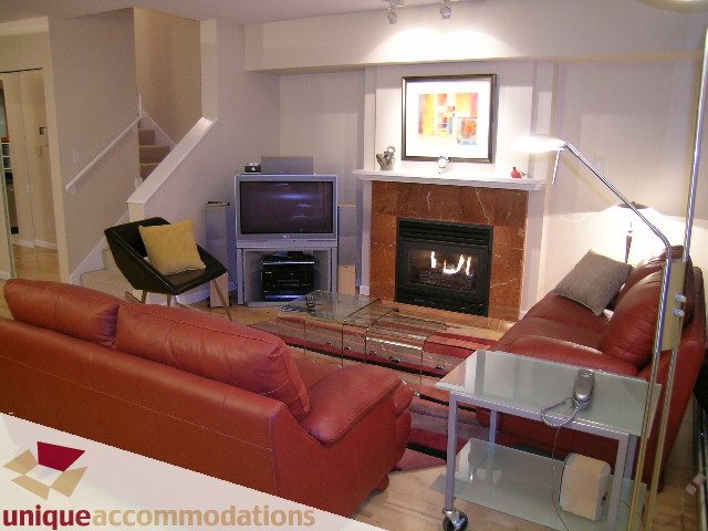 Living room with red leather couch, glass coffee table, and fireplace. - 322 - 1228 Marinaside Crescent, Vancouver Downtown