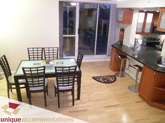 Furnished dining area with hardwood floors and a sliding glass door leading to a patio. - 322 - 1228 Marinaside Crescent, Vancouver Downtown