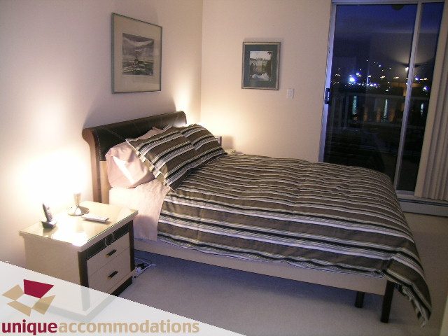 Furnished bedroom with striped bedding and city view through large window. - 322 - 1228 Marinaside Crescent, Vancouver Downtown
