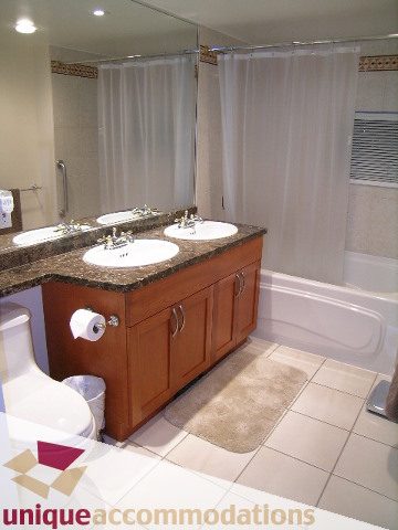 Furnished bathroom with dual sinks, granite countertops, and a large shower. - 322 - 1228 Marinaside Crescent, Vancouver Downtown