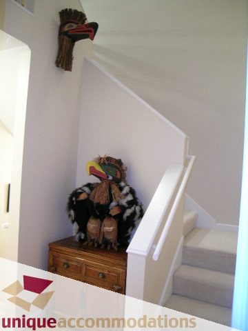 Staircase leading to upper level with wooden dresser and decorative mask. - 322 - 1228 Marinaside Crescent, Vancouver Downtown