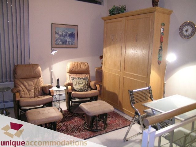 Furnished living room with leather recliners, wooden cabinet, and patterned rug. - 322 - 1228 Marinaside Crescent, Vancouver Downtown