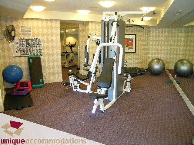 Bright and modern gym with various exercise equipment and checkered wallpaper. - 322 - 1228 Marinaside Crescent, Vancouver Downtown