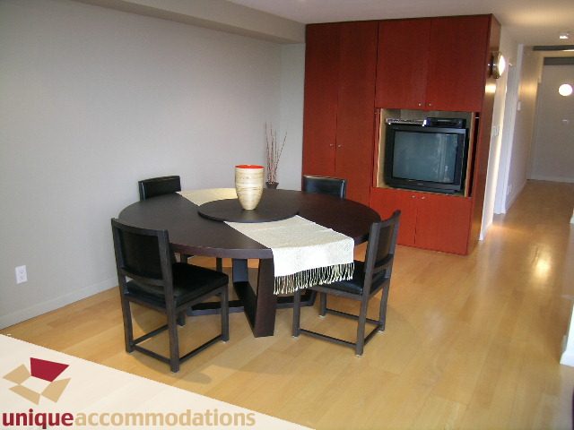 Bright dining and living area with hardwood floors, modern furniture, and a built-in entertainment unit.