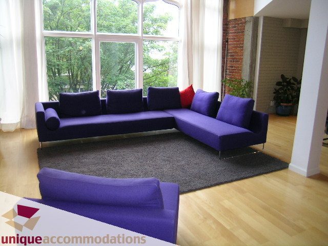 Furnished living room with purple sectional, hardwood floors, and large windows. - 401 - 2525 Quebec Street, Vancouver East Side