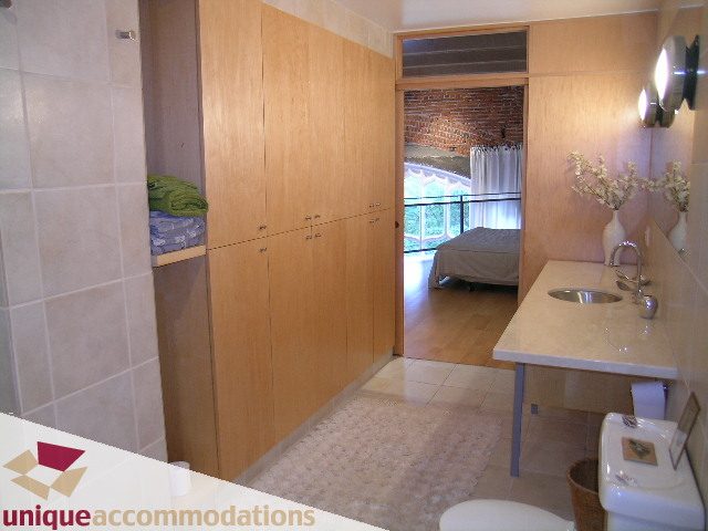 Furnished bathroom with wooden cabinets, tiled walls, and a view of the balcony. - 401 - 2525 Quebec Street, Vancouver East Side
