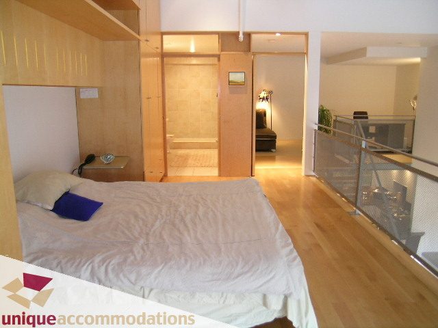 Furnished 1-bedroom with hardwood floors and a cozy bed setup. - 401 - 2525 Quebec Street, Vancouver East Side