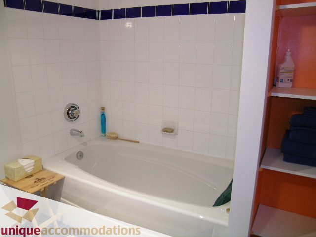 Bathroom with white tile, bathtub, and orange shelving. - 401 - 2525 Quebec Street, Vancouver East Side
