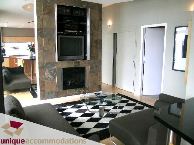 Furnished living room with a checkered rug, modern fireplace, and sleek countertops. - 2502 - 1077 Marinaside Crescent, Vancouver Downtown