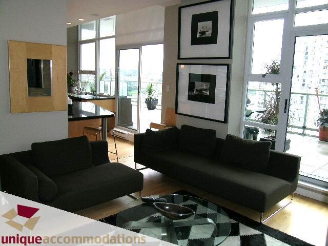 Bright living room with hardwood floors, city view, and modern furniture. - 2502 - 1077 Marinaside Crescent, Vancouver Downtown