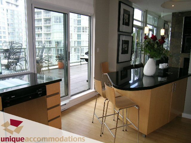 Furnished kitchen with black countertops, hardwood floors, and city view. - 2502 - 1077 Marinaside Crescent, Vancouver Downtown