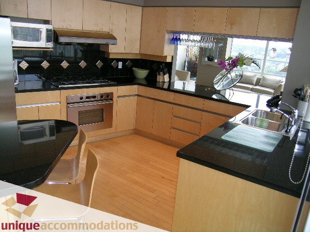 Furnished kitchen with black countertops, hardwood floors, and a city view. - 2502 - 1077 Marinaside Crescent, Vancouver Downtown