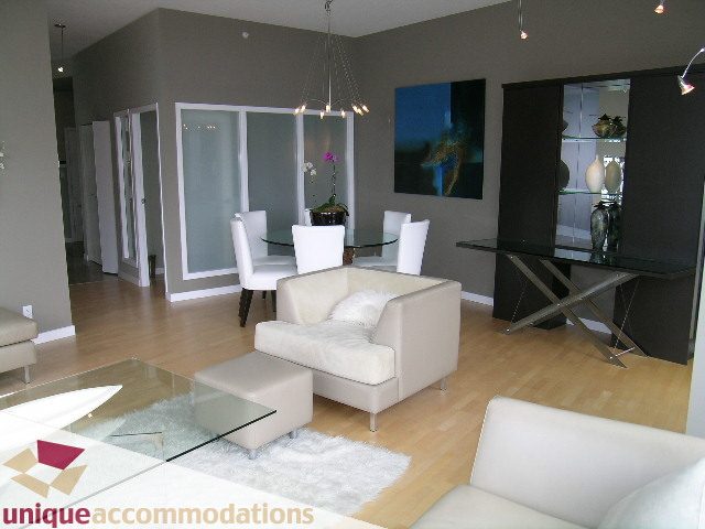 Furnished dining area with modern glass table, white chairs, and hardwood floors. - 2502 - 1077 Marinaside Crescent, Vancouver Downtown