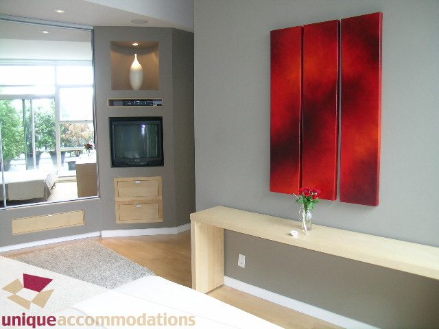 Bright living room with modern decor, red accent wall, hardwood floors, and city view. - 2502 - 1077 Marinaside Crescent, Vancouver Downtown