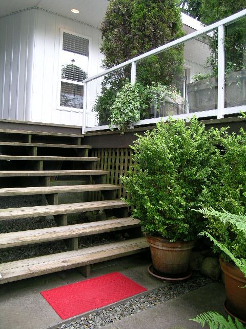 Furnished entryway with wooden steps, potted plants, and a red mat. - 470 Ellis Street, North Vancouver