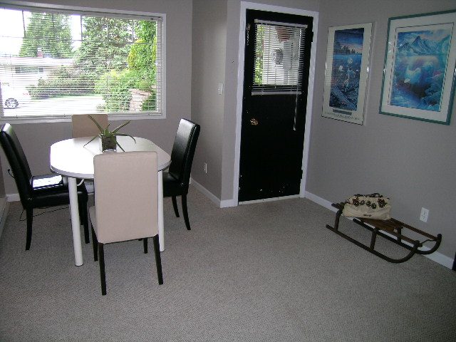Bright dining area with a round table, black chairs, and a window view of greenery. - 470 Ellis Street, North Vancouver