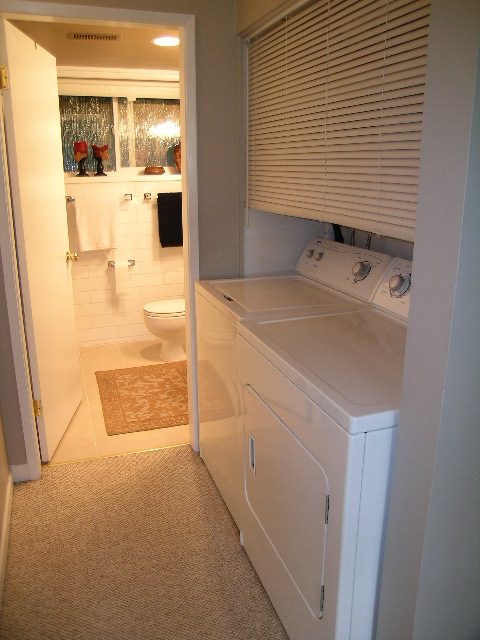 Furnished laundry room with white appliances and beige carpet. - 470 Ellis Street, North Vancouver