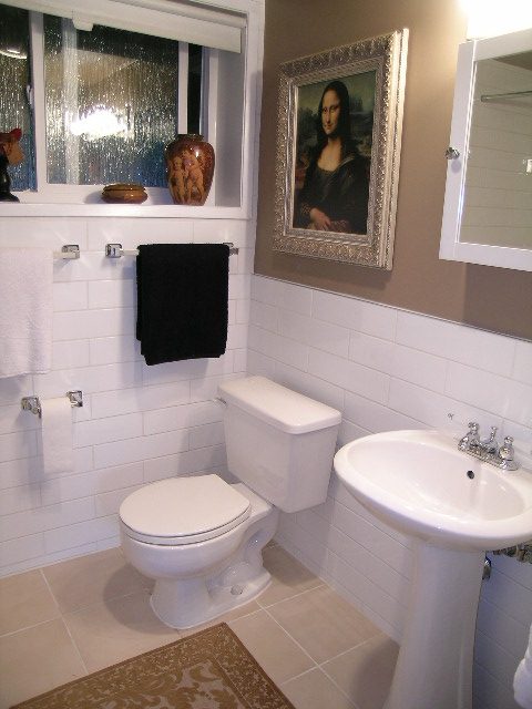 Bathroom with white tiles, sink, toilet, and framed Mona Lisa. - 470 Ellis Street, North Vancouver