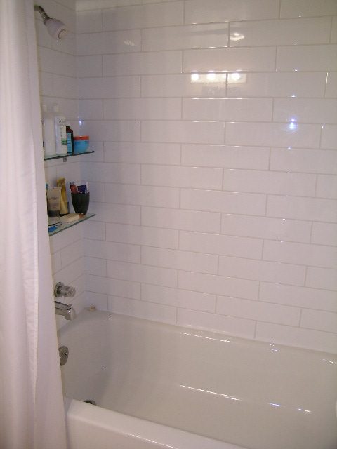 Bathroom with white subway tiles and a corner shelf holding toiletries. - 470 Ellis Street, North Vancouver