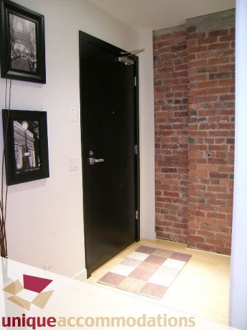 Loft with exposed brick walls, hardwood floors, and a checkered rug. - 409 - 1072 Hamilton Street, Vancouver Downtown