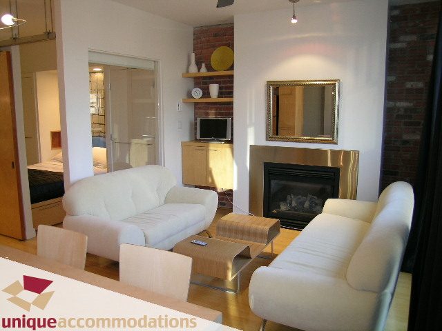 Furnished living room with white furniture, brick wall, and modern decor. - 409 - 1072 Hamilton Street, Vancouver Downtown