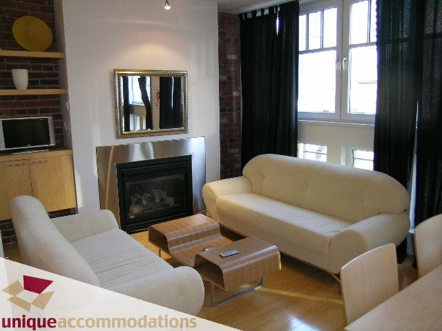 Furnished living room with modern furniture, brick wall, and large windows. - 409 - 1072 Hamilton Street, Vancouver Downtown