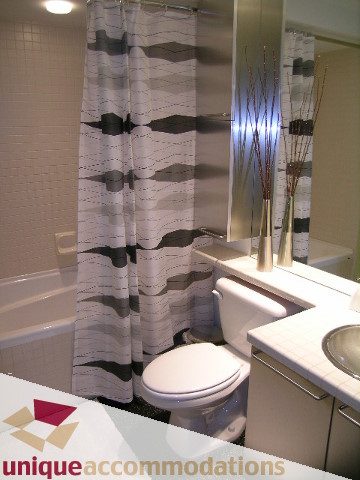 Furnished bathroom with modern shower curtain and white countertop. - 409 - 1072 Hamilton Street, Vancouver Downtown