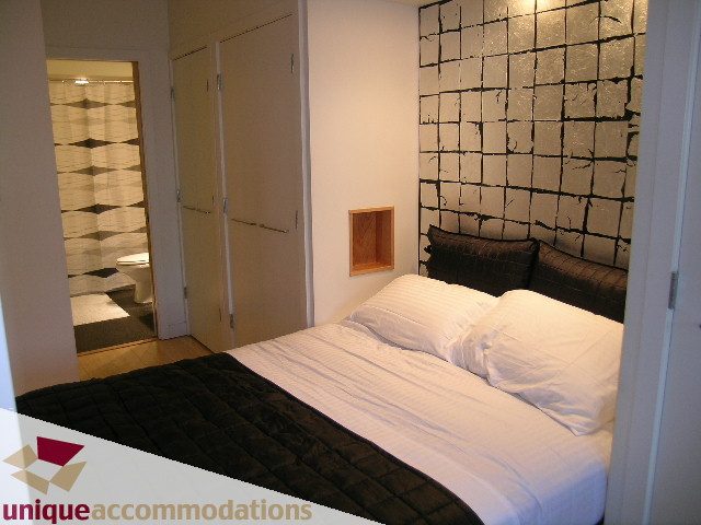 Bright bedroom with modern black and white decor, large bed, and wall art. - 409 - 1072 Hamilton Street, Vancouver Downtown