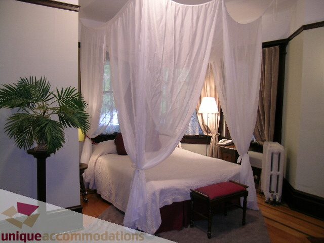 Furnished bedroom with canopy bed, hardwood floors, and a potted palm. - 3 - 2812 Yukon, Vancouver West Side