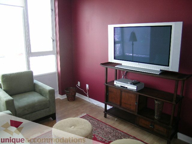 Living room with maroon walls, wooden entertainment stand, and a large flat-screen TV. - 3607 - 1033 Marinaside Crescent, Vancouver Downtown