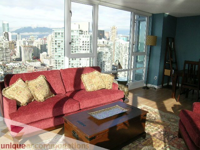 Furnished living room with red couch, city view, hardwood floors, and wooden coffee table. - 3607 - 1033 Marinaside Crescent, Vancouver Downtown