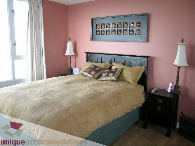 Furnished bedroom with pink walls, wooden headboard, and bedside lamps. - 3607 - 1033 Marinaside Crescent, Vancouver Downtown
