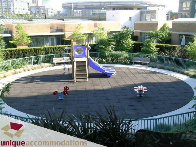 Playful children's playground with slide and sandbox, surrounded by greenery and city views. - 3607 - 1033 Marinaside Crescent, Vancouver Downtown