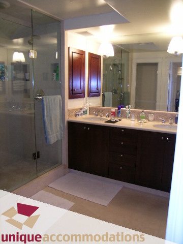 Furnished bathroom with dark wood cabinets and a large mirror. - 4497 Marine Dr., West Vancouver