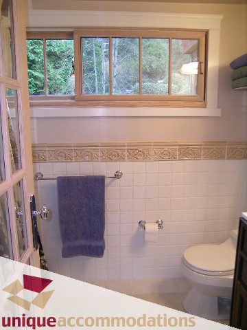 Bathroom with large window, white tile walls, and purple towels. - 4497 Marine Dr., West Vancouver