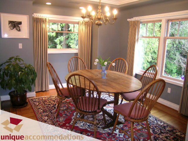 Dining area with wooden chairs, chandelier, and large windows. - 4497 Marine Dr., West Vancouver