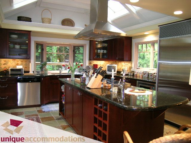Bright kitchen with dark wood cabinets, granite countertops, and a large island. - 4497 Marine Dr., West Vancouver