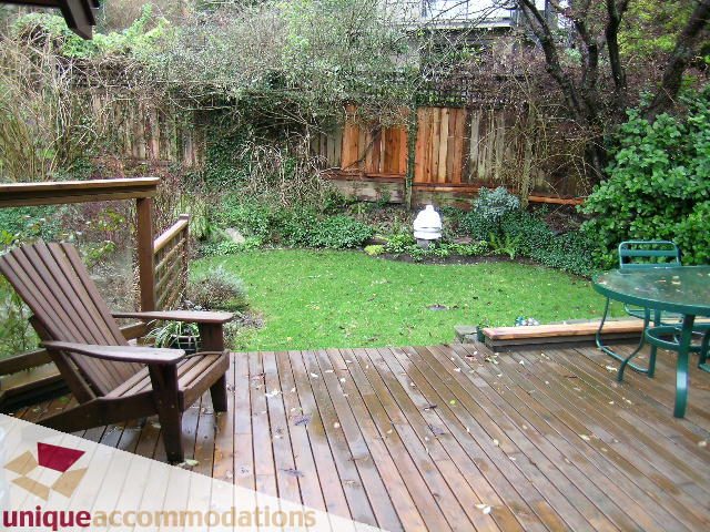 Furnished deck with wooden flooring and outdoor seating, surrounded by lush greenery. - 4497 Marine Dr., West Vancouver