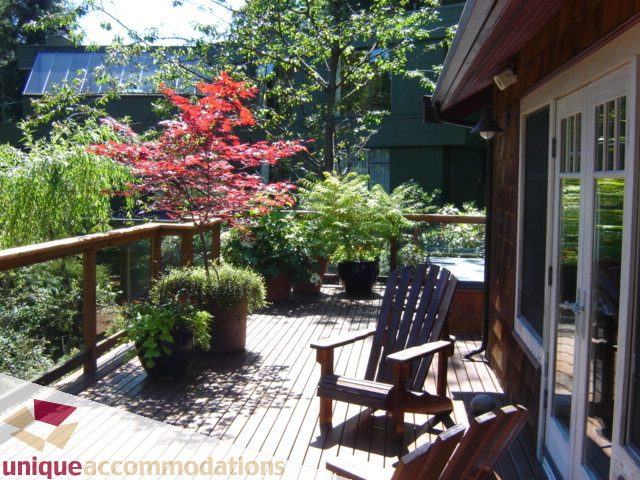 Furnished deck with wooden chairs, potted plants, and a red maple tree. - 4497 Marine Dr., West Vancouver