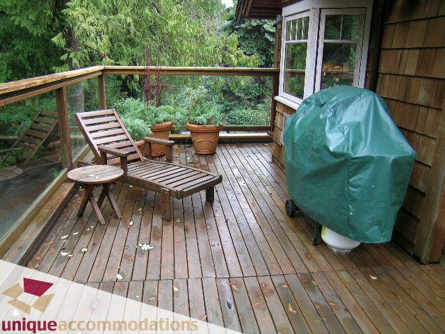 Furnished deck with wooden flooring, outdoor furniture, and a covered grill. - 4497 Marine Dr., West Vancouver