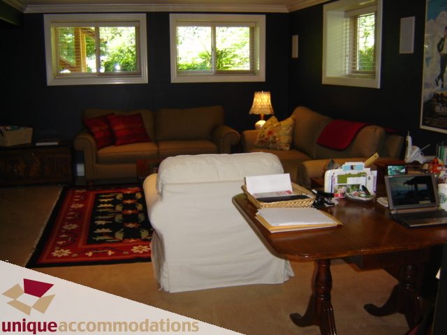 Furnished living room with dark walls, patterned rug, and cozy seating. - 4497 Marine Dr., West Vancouver