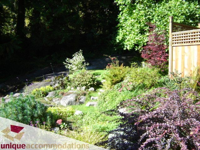 Furnished garden with lush greenery and wooden deck. - 4497 Marine Dr., West Vancouver