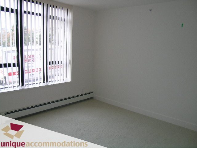 Bright living room with large window and carpeted floor. - 108 - 175 West 1st Street, North Vancouver