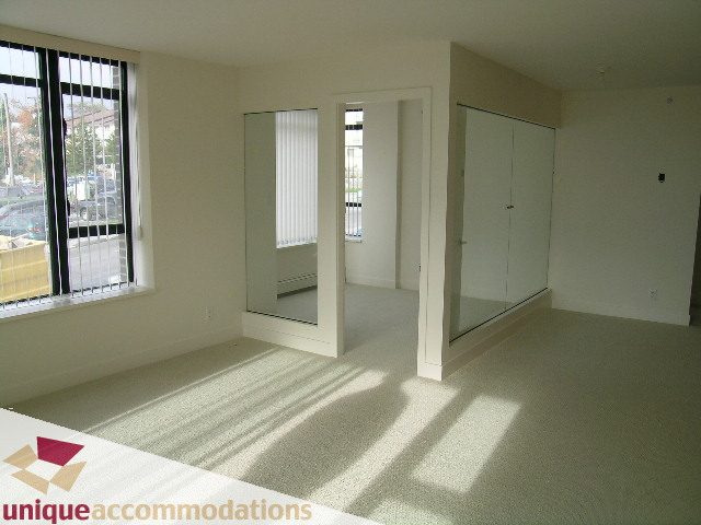 Spacious living room with large windows, hardwood floors, and a city view. - 108 - 175 West 1st Street, North Vancouver