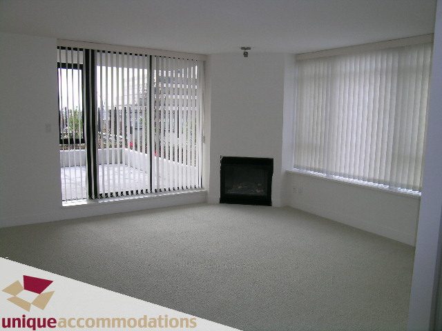 Bright living room with large windows, white blinds, and carpeted floor. - 108 - 175 West 1st Street, North Vancouver