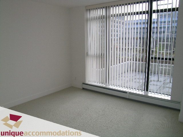 Bright living room with large window, city view, and carpeted floor. - 108 - 175 West 1st Street, North Vancouver