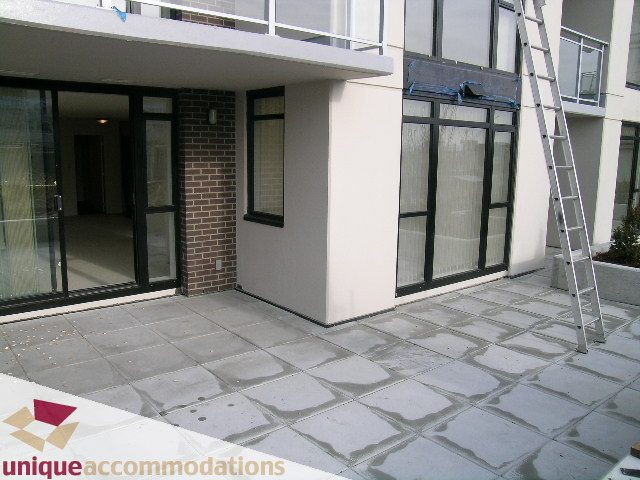Furnished living room with large windows, modern design, and tiled patio. - 108 - 175 West 1st Street, North Vancouver