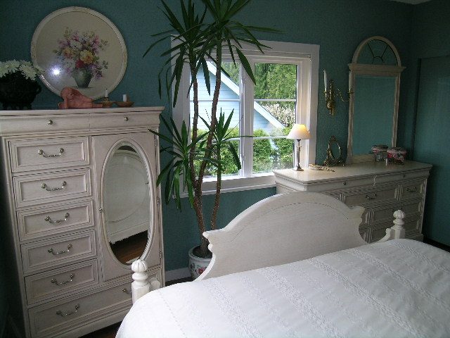 Cozy bedroom with teal walls, white furniture, and a large window with a view. - 2679 Ottawa Ave, West Vancouver