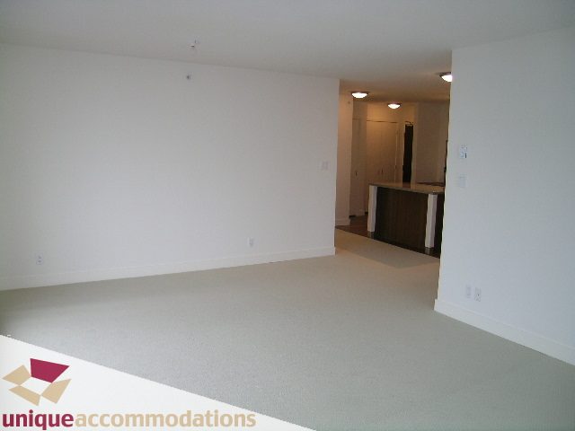 Open living space with light-colored carpet and modern kitchen counter. - 1404 - 155 W. 1st Street, North Vancouver