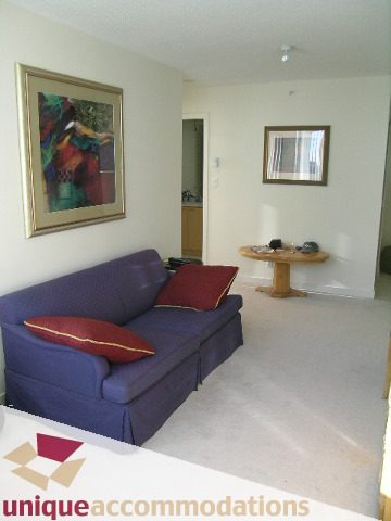 Furnished living room with blue couch, red pillows, and small table. - 2406 - 1200 West Georgia Street, Vancouver Downtown